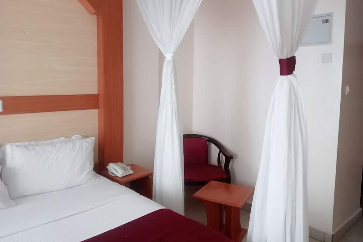 A hotel room with a bed, a small table, a chair, and a nightstand with a phone.