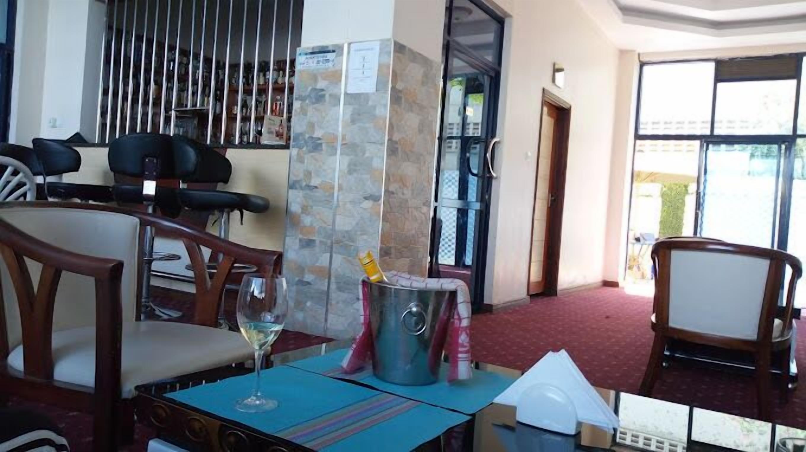 A hotel room with a dining area, a stone pillar, a minibar, and a view of the outside.