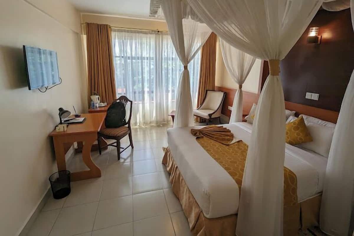 A hotel room with a bed, a desk, a chair, and a TV.