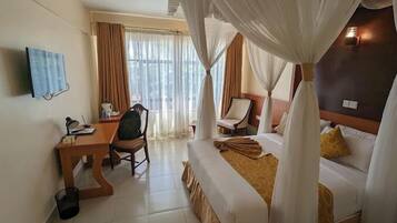 A hotel room with a bed, a desk, a chair, and a TV.