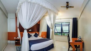 Une chambre à coucher avec un lit à baldaquin, un bureau et une vue sur l’extérieur.