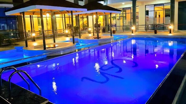 Une piscine à l’eau bleue, entourée d’un espace de détente abrité et agrémenté de parasols.