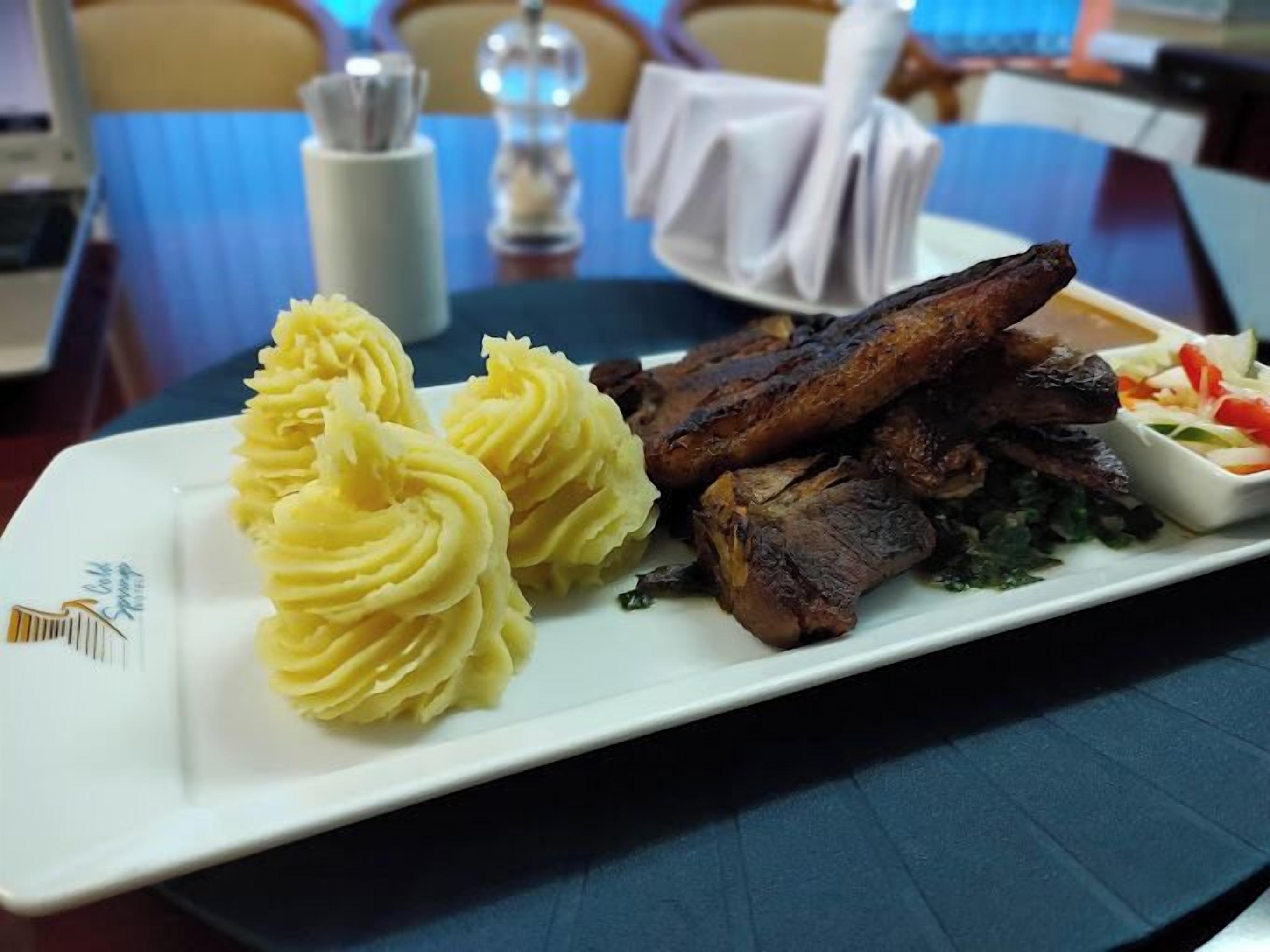 A plate with mashed potatoes, grilled meat, and a side salad on a white rectangular plate.