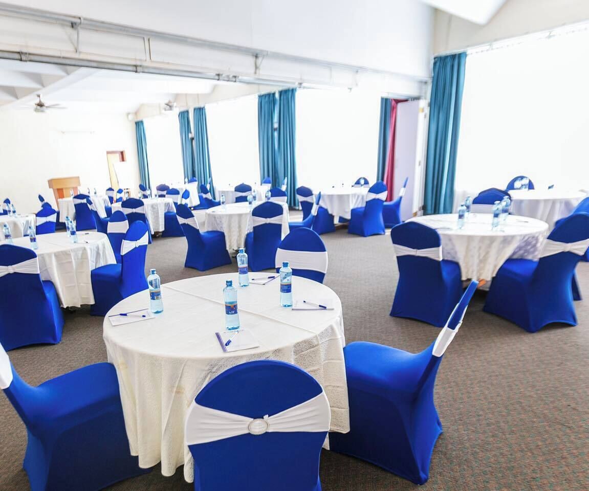 A conference room with round tables, blue chairs, and white tablecloths.