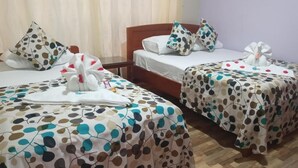A hotel room with two beds, each with a polka dot bedspread and a white towel with a flower design. - HOTEL DESTINO AVENTURA PERU (Chanchamayo)