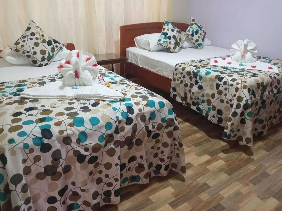 A hotel room with two beds, each with a polka dot bedspread and a white towel with a flower design.