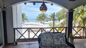 A room with a view of a beach, a wicker sofa, and a hanging light fixture. - Casa Columpios playa alberca terraza familiar (Progreso)