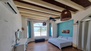 A bedroom with a wooden floor, a bed, a desk, a chair, a window with curtains, and a ceiling fan. - Casa Columpios playa alberca terraza familiar (Progreso)