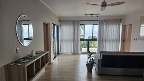 Una camera spaziosa con un'ampia finestra, un ventilatore a soffitto, un divano e un tavolino consolle.