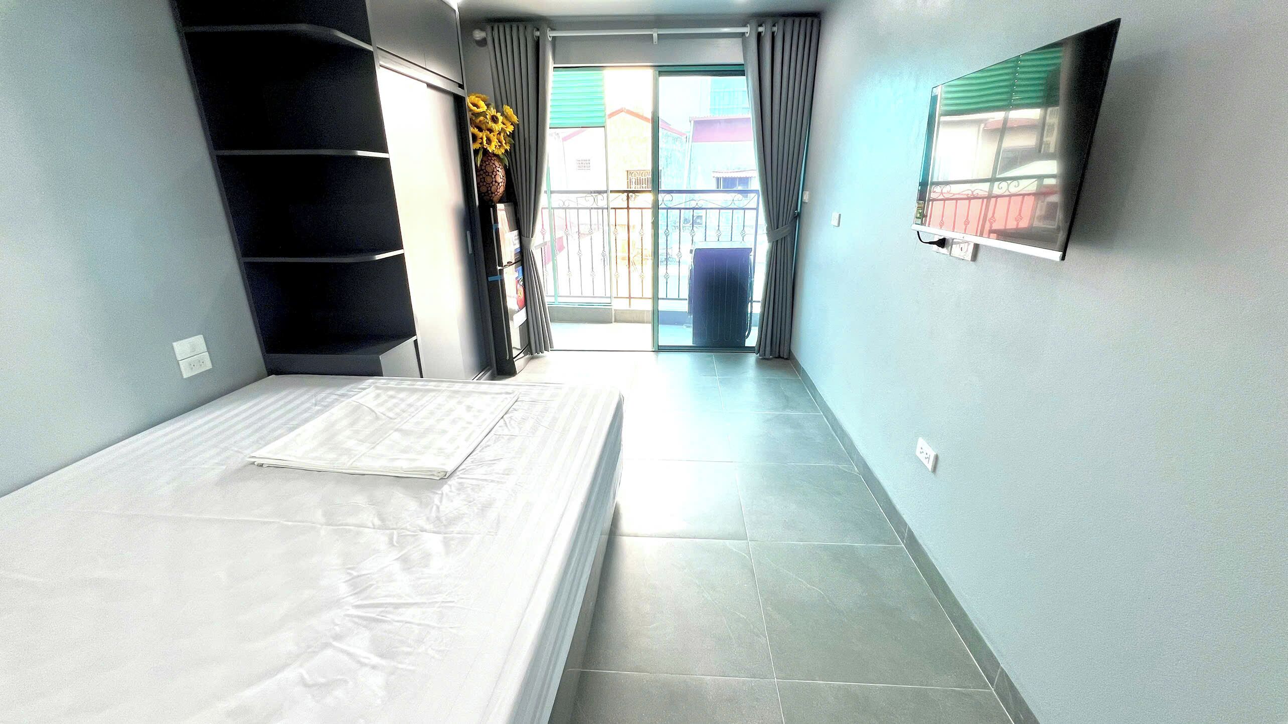 A narrow room with a bed, a window, and a door leading to a balcony.