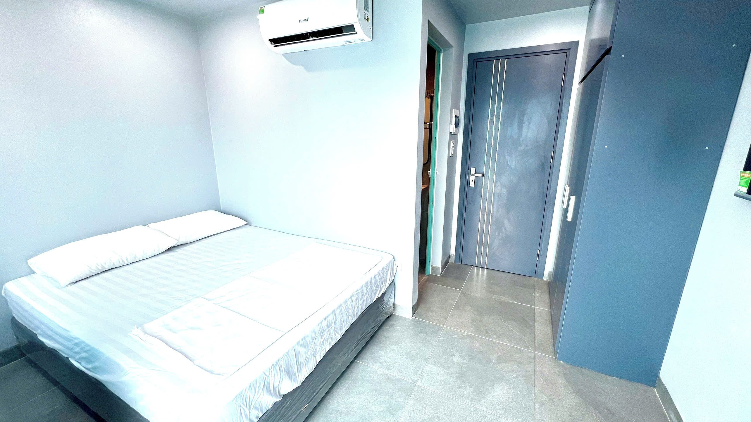 Une chambre d’hôtel avec un lit, une porte et un appareil de climatisation.