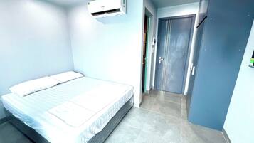 Une chambre d’hôtel avec un lit, une porte et un appareil de climatisation.