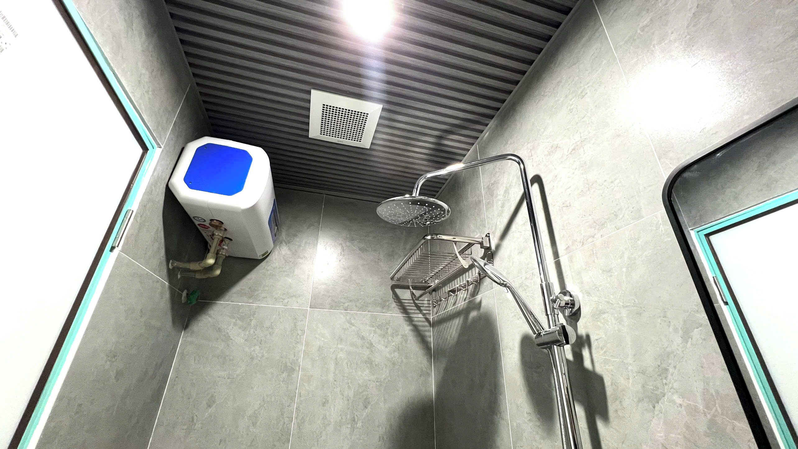 Baño con ducha, inodoro y sistema de ventilación.
