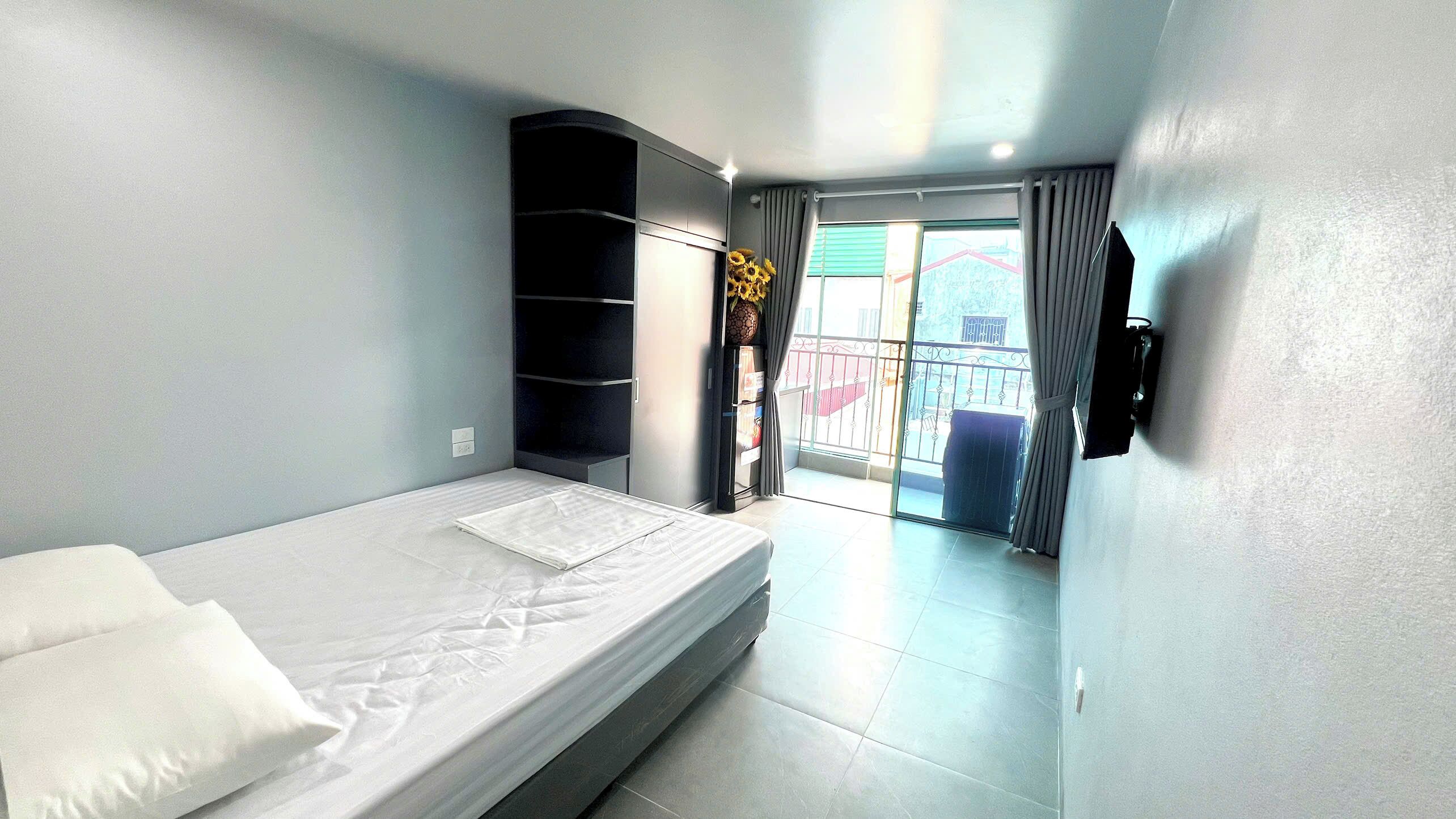 Une chambre d’hôtel comprenant un lit, une armoire intégrée, une petite table, un téléviseur fixé au mur et un balcon avec vue.