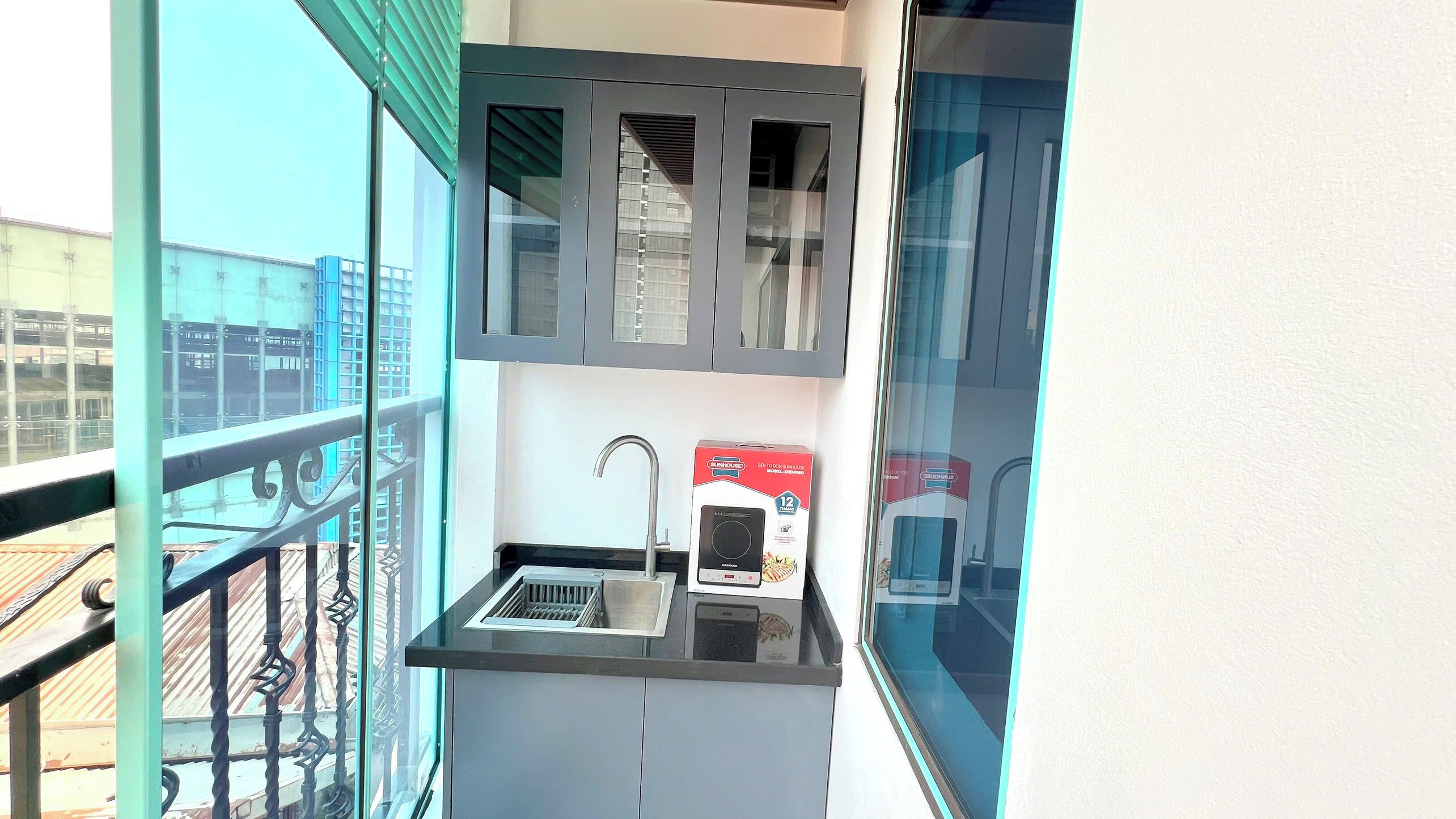 A small kitchen with a sink, a microwave, and a box of a 12-inch electric kettle.