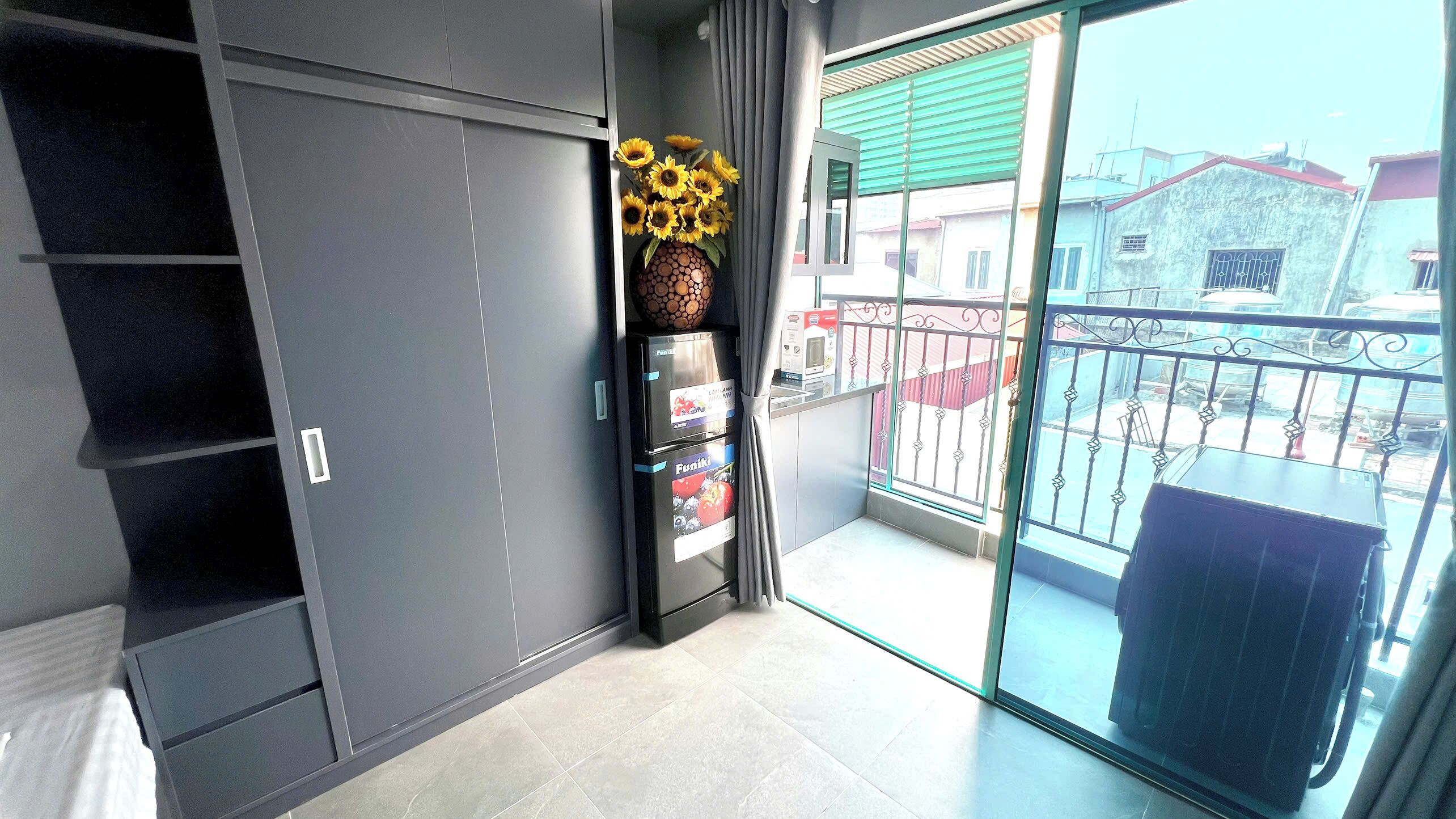 En moderne lejlighed med skydedør til en balkon, indbygget skab og en vase med solsikker.