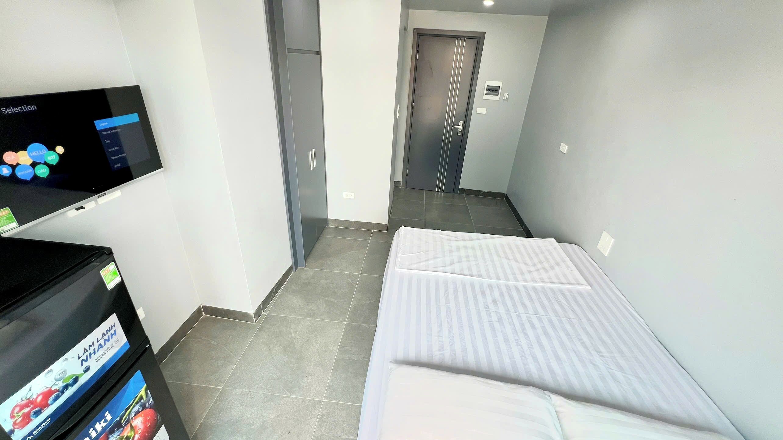 Een hotelkamer met een bed, een televisie op een standaard en een minibar.