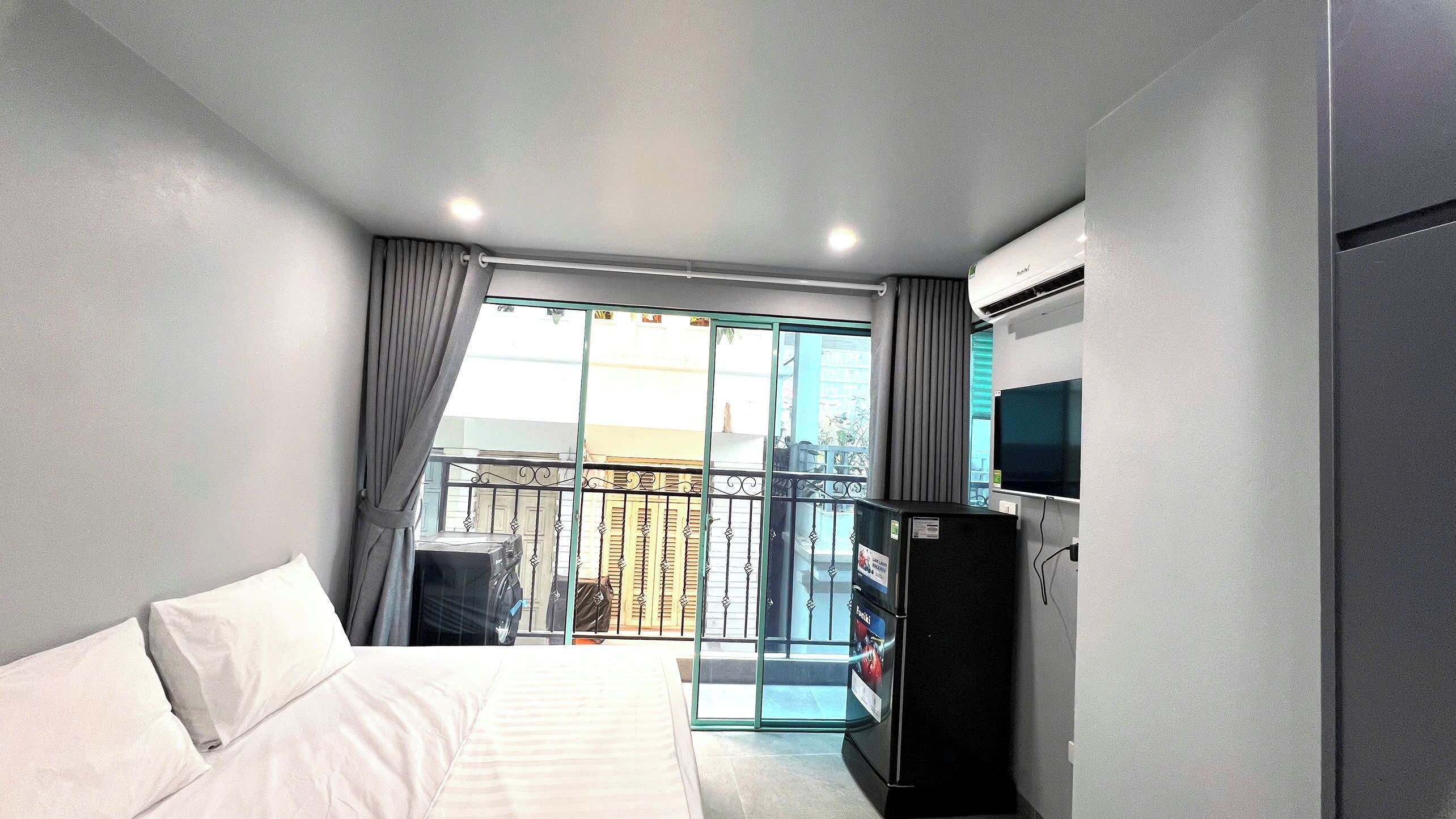 Habitación de hotel con cama, televisión, refrigerador y balcón con vistas.