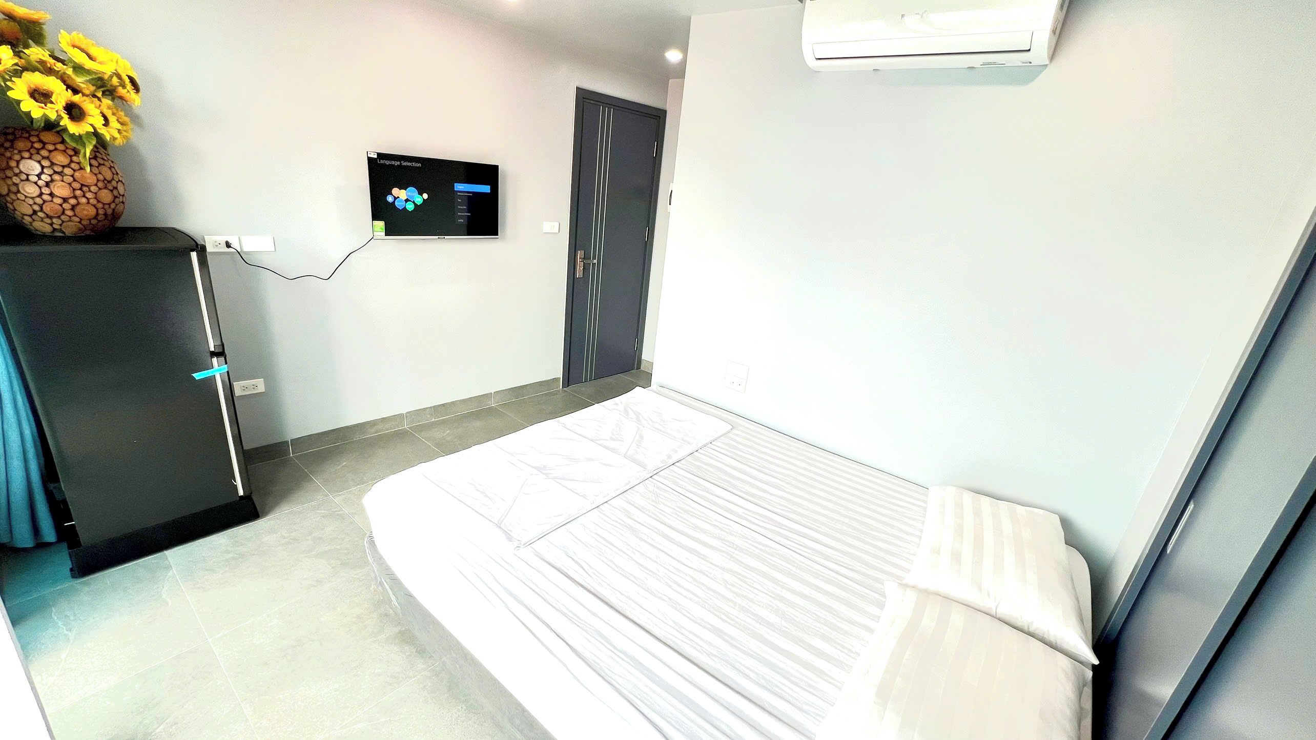 Een hotelkamer met een bed, een bureau, een stoel, een vaas met bloemen en een tv aan de muur.