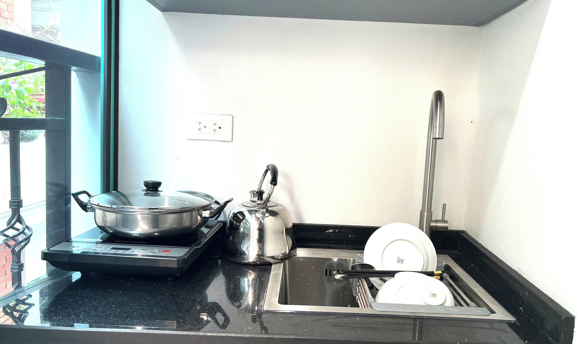 A compact kitchen with a stove, kettle, and sink.