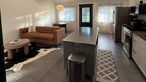 Eine moderne Küche mit Kochinsel, ein Essbereich mit einer Couch und ein Wohnzimmer mit Couchtisch.