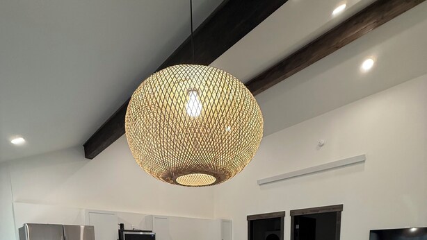 Eine moderne Küche mit Edelstahlgeräten, ein Essbereich mit Holztisch und eine große Pendelleuchte.