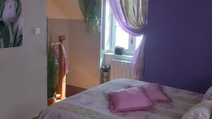 A bedroom with a bed, purple curtains, a window, and a wall clock.