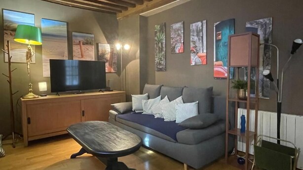 A living room with a sofa, a coffee table, a TV, and artwork on the walls.