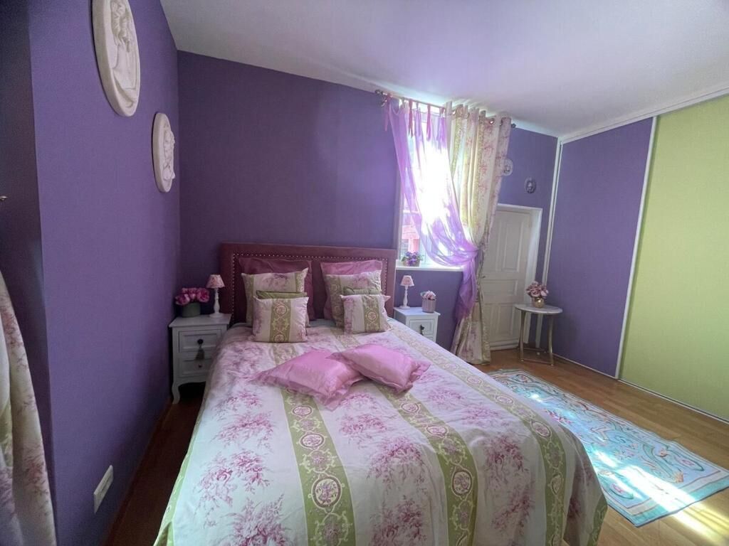 A bedroom with a bed, nightstands, a window with curtains, and a door.