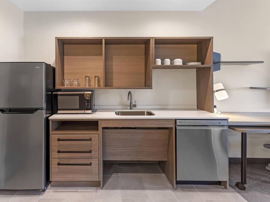 A compact kitchen with a refrigerator, microwave, sink, and dishwasher.
