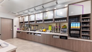 A modern coffee shop with a counter, coffee machines, and shelves with cups and glasses. - Home2 Suites By Hilton Calera (Calera)
