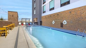 A swimming pool with a brick wall, a lifebuoy, and outdoor seating. - Home2 Suites By Hilton Calera (Calera)