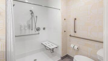 Un baño moderno con ducha, inodoro y barras de apoyo.