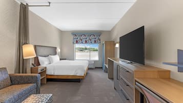 A hotel room with a bed, a TV, a desk, and a chair.