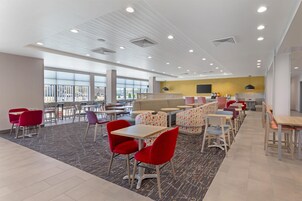 Una cafetería moderna con techos altos, amplias ventanas y diversas opciones de asientos, como mesas y sillas.