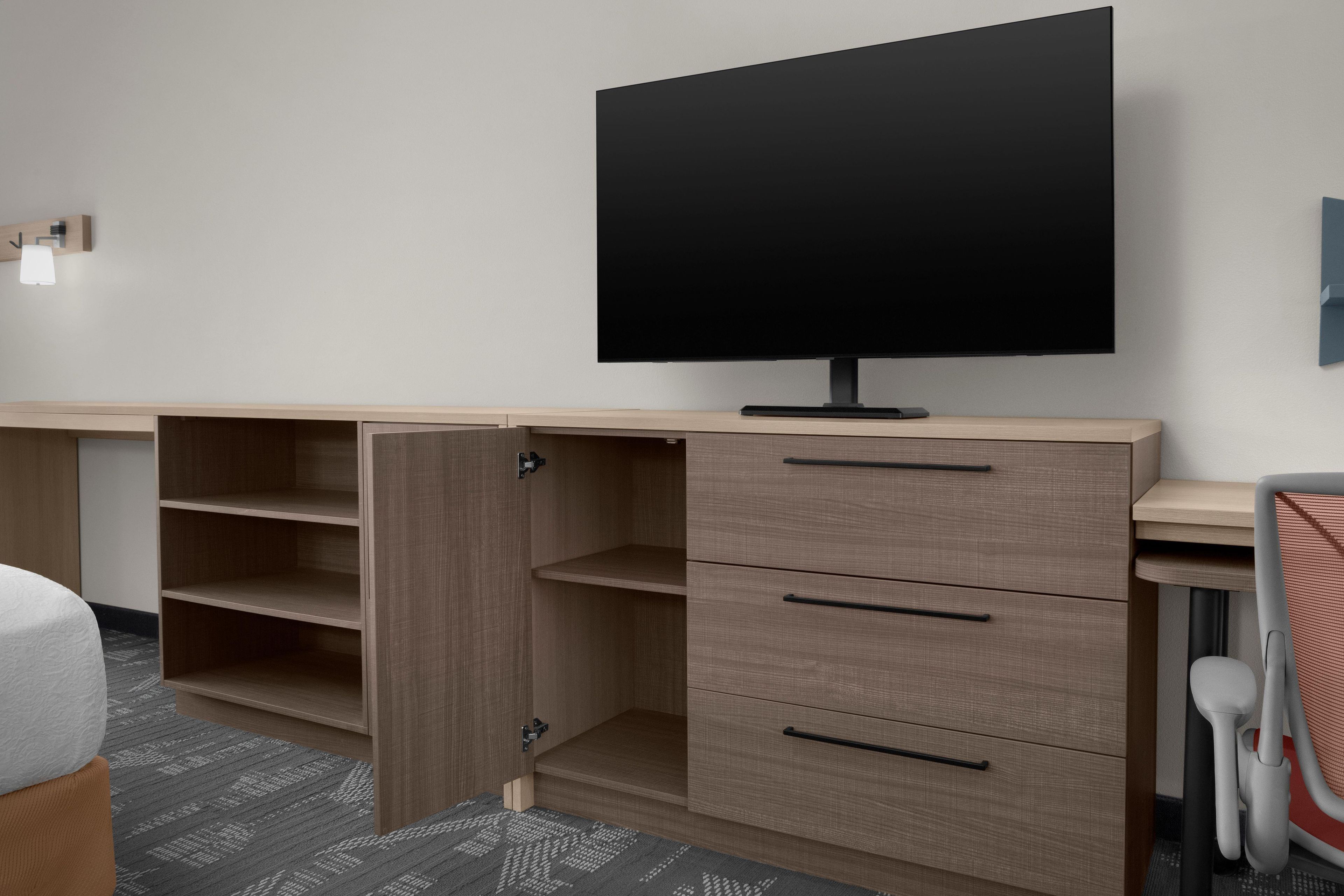 Una habitación moderna con televisión de pantalla plana, muebles de madera y un espacio de escritorio.