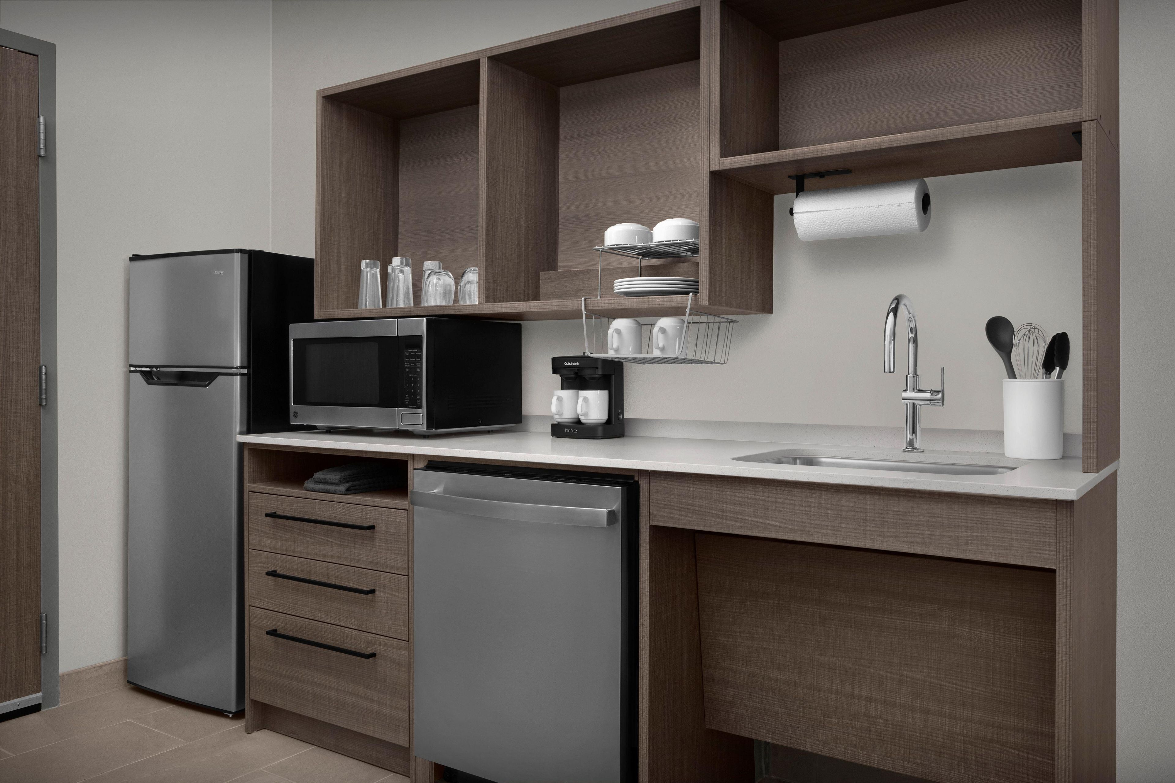 A modern kitchen with a refrigerator, microwave, dishwasher, and wooden cabinets.