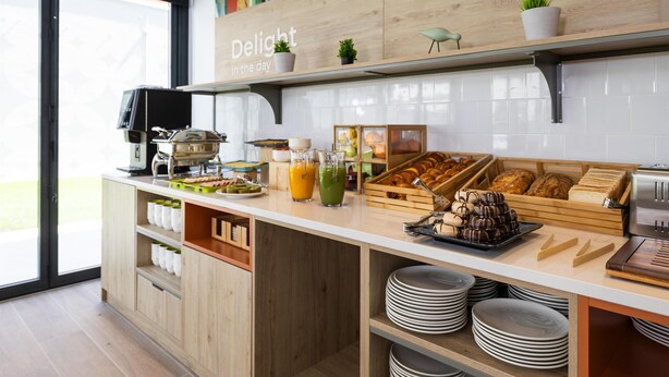 Una cocina moderna con cafetera, productos para el desayuno y un cartel que dice 'Delight in the day'.