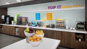 A breakfast area with a sign reading "TOP IT BREAKFAST" and various food options like pancakes and eggs. - Tru By Hilton Joliet Plainfield (Joliet)
