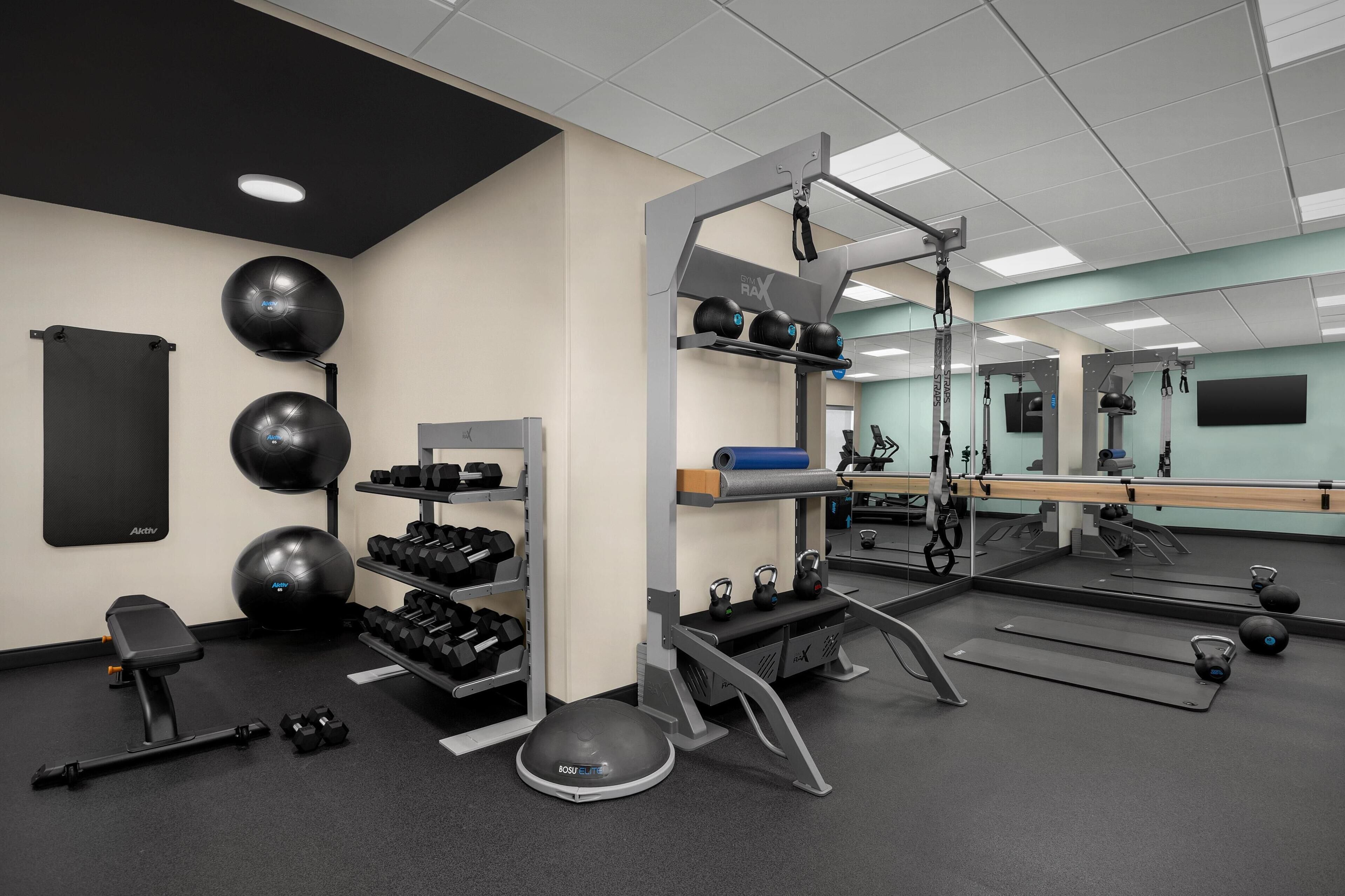 A gym with exercise equipment, a bench, dumbbells, and a mirror.