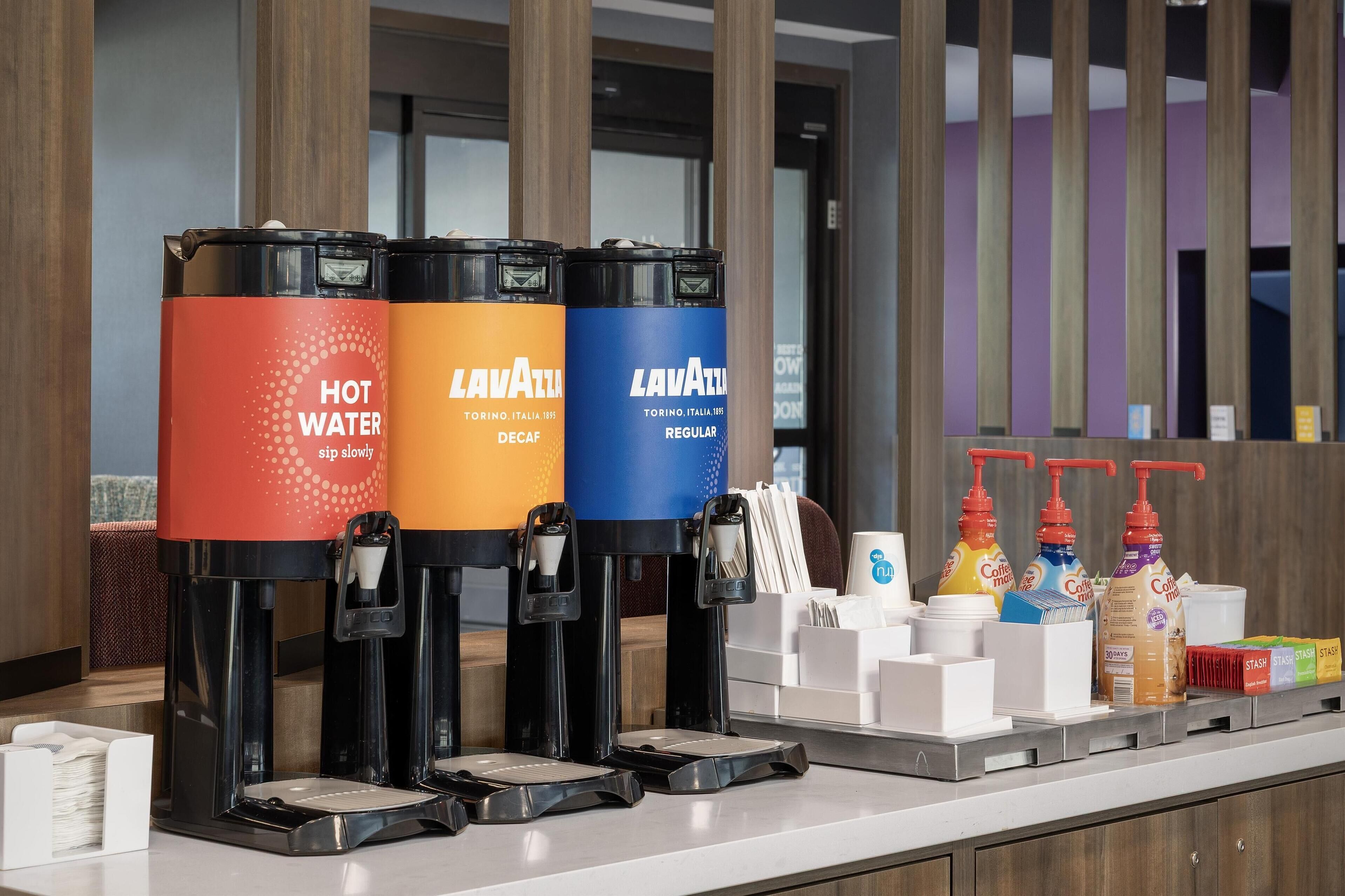 Una estación de café con tres dispensadores etiquetados como “AGUA CALIENTE”, “LAVATTL” y “LAVATTL REGULAR”.