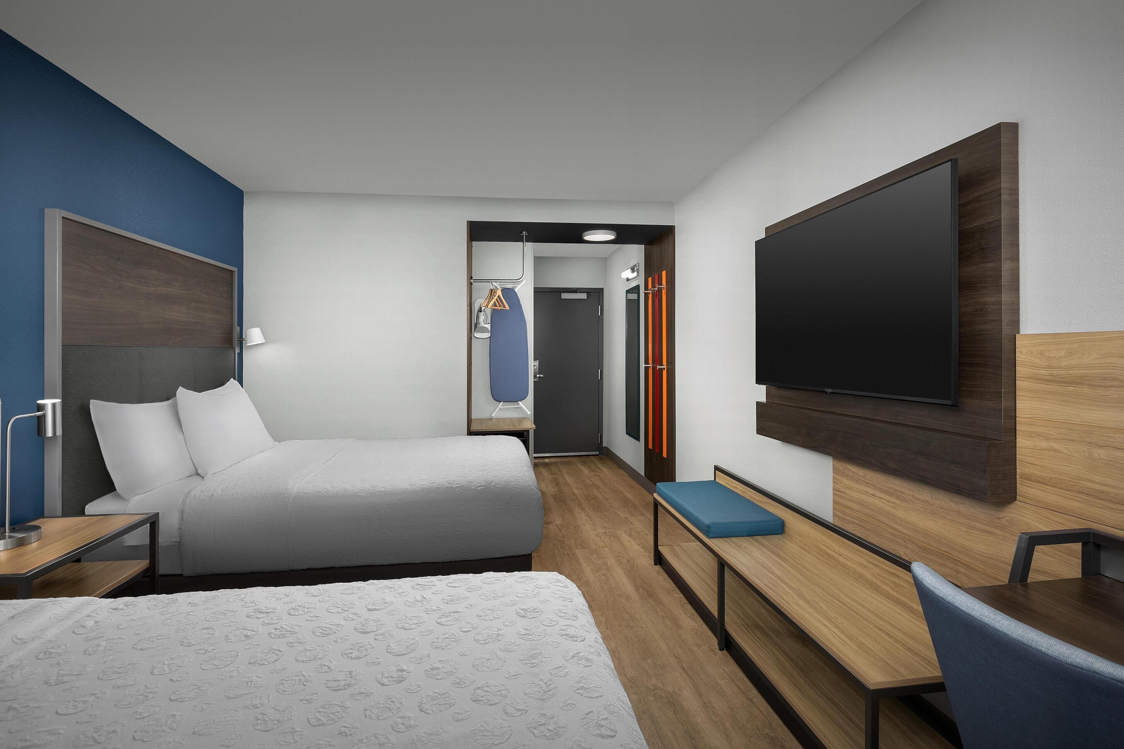 Una habitación de hotel moderna con una cama grande, un escritorio, un televisor de pantalla plana y una zona de estar.