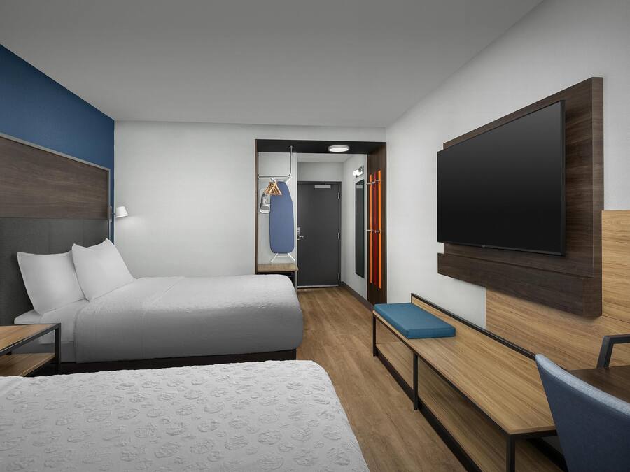 Una habitación de hotel moderna con una cama grande, un escritorio, un televisor de pantalla plana y una zona de estar.