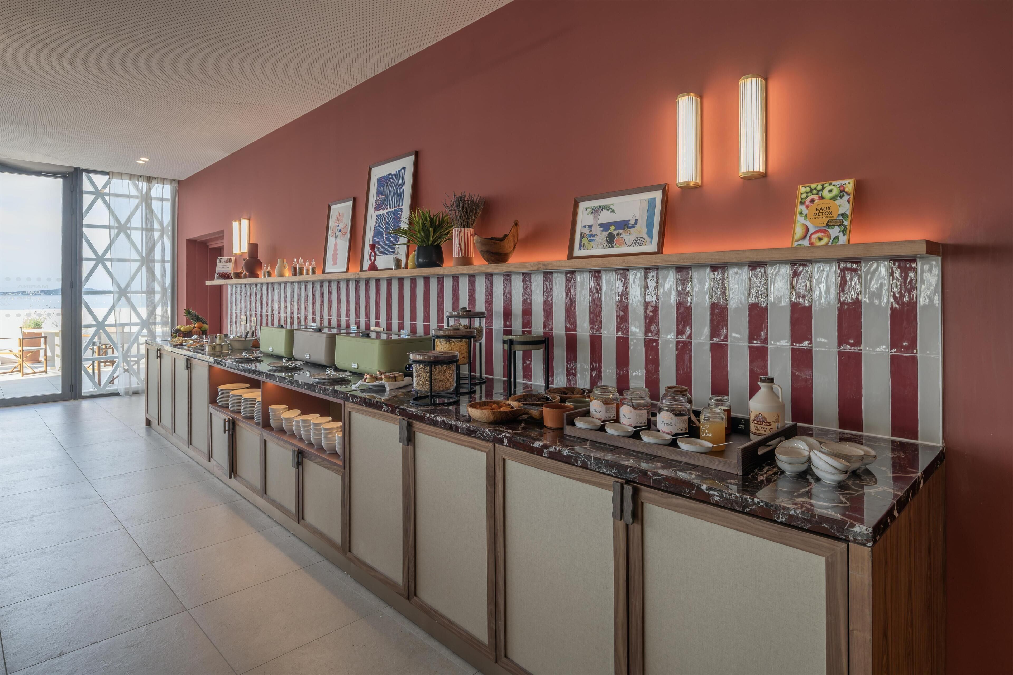 A hotel reception area with a long counter, various food items, and a view through a glass door.