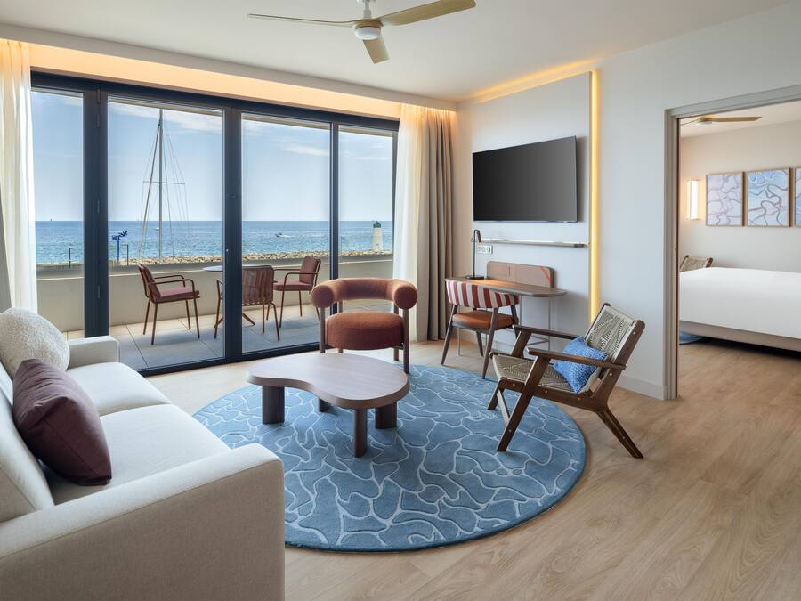 Ein Hotelzimmer mit großem Balkon, einer Couch, einem Couchtisch und einem Bett.