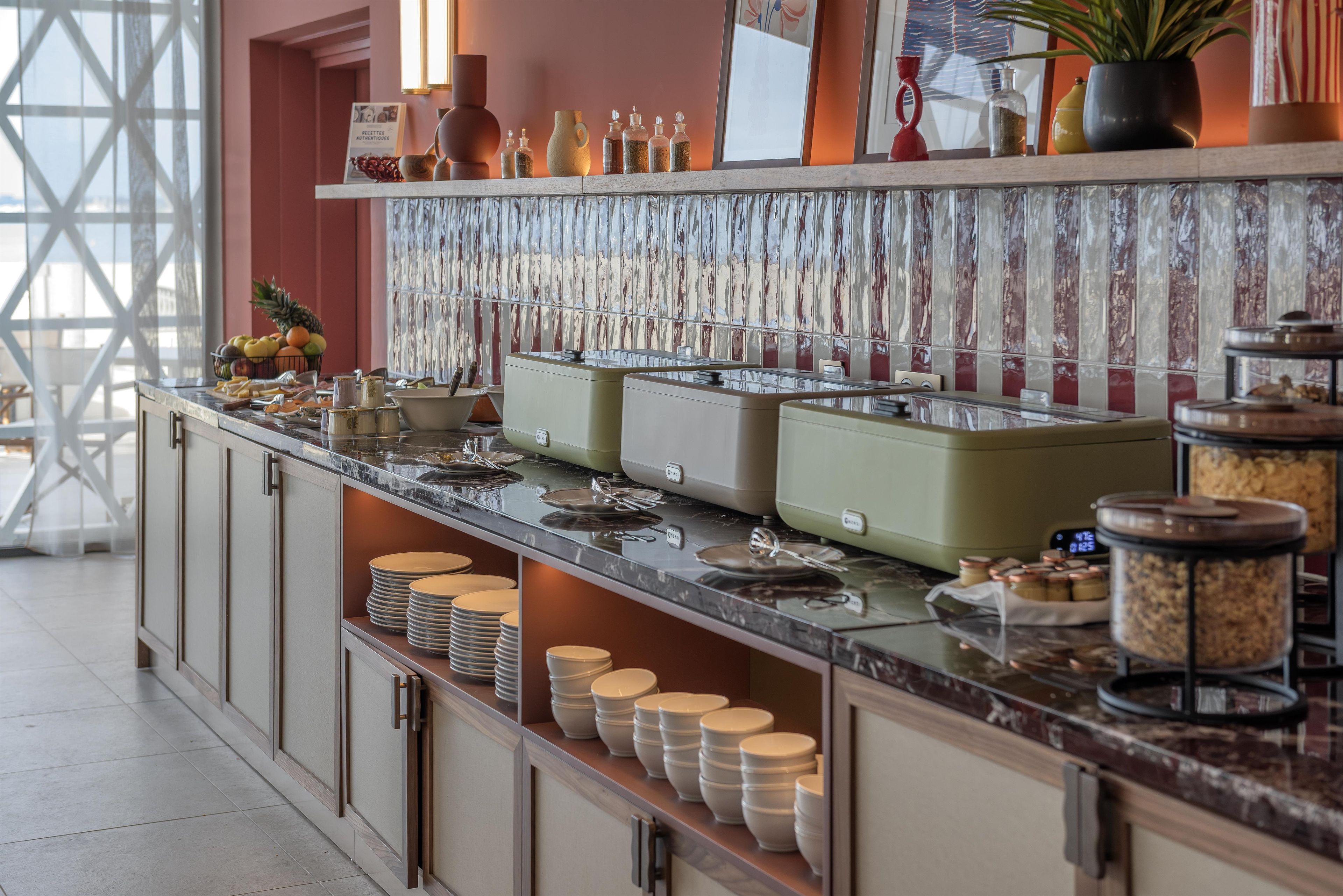 Una barra de buffet con diversos recipientes de comida y utensilios.