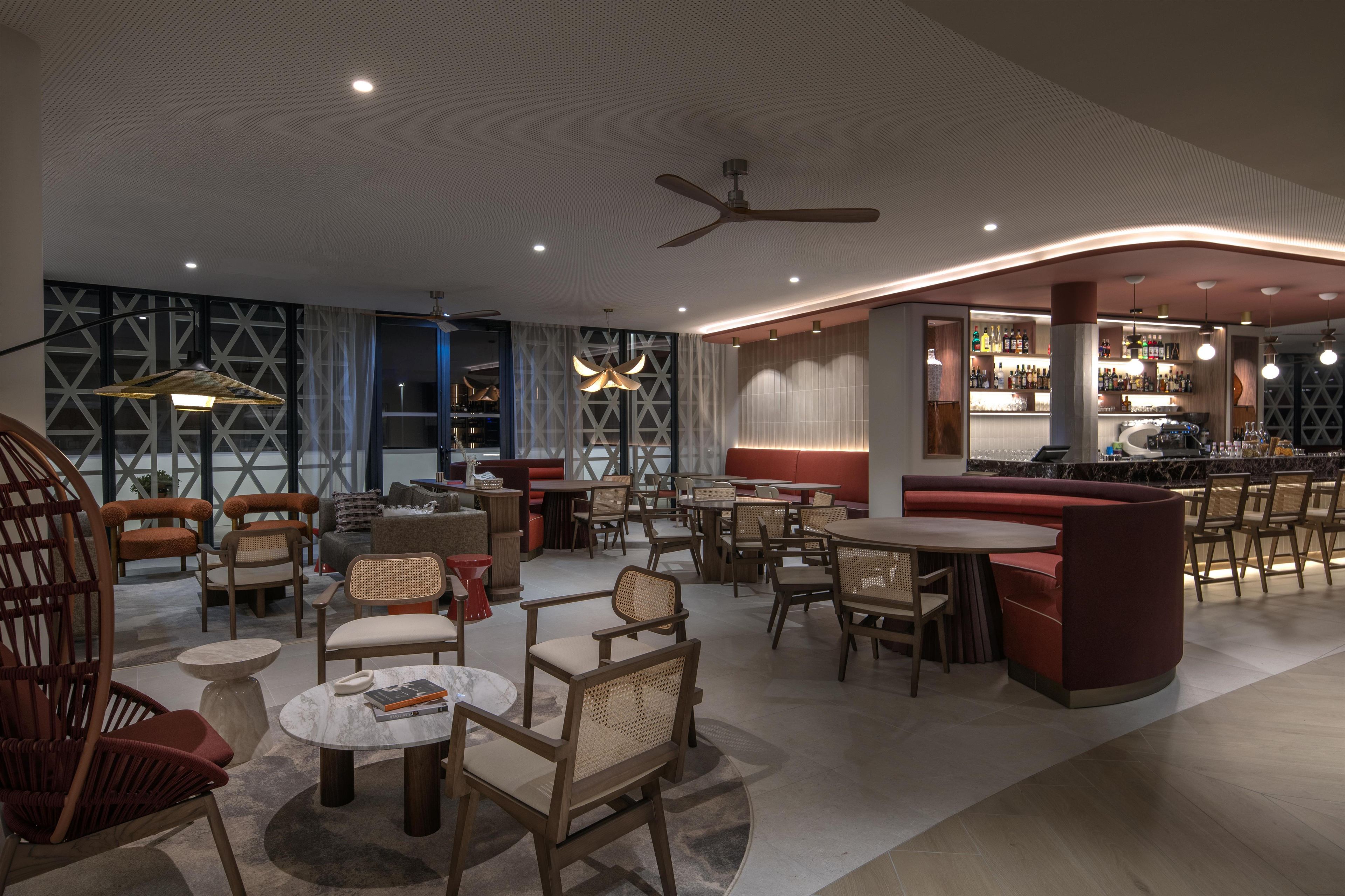 A modern interior with seating areas, a bar, and a ceiling fan.
