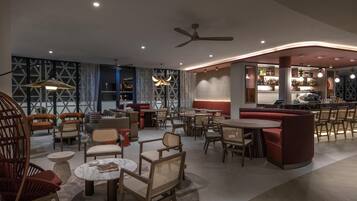 A modern interior with seating areas, a bar, and a ceiling fan.