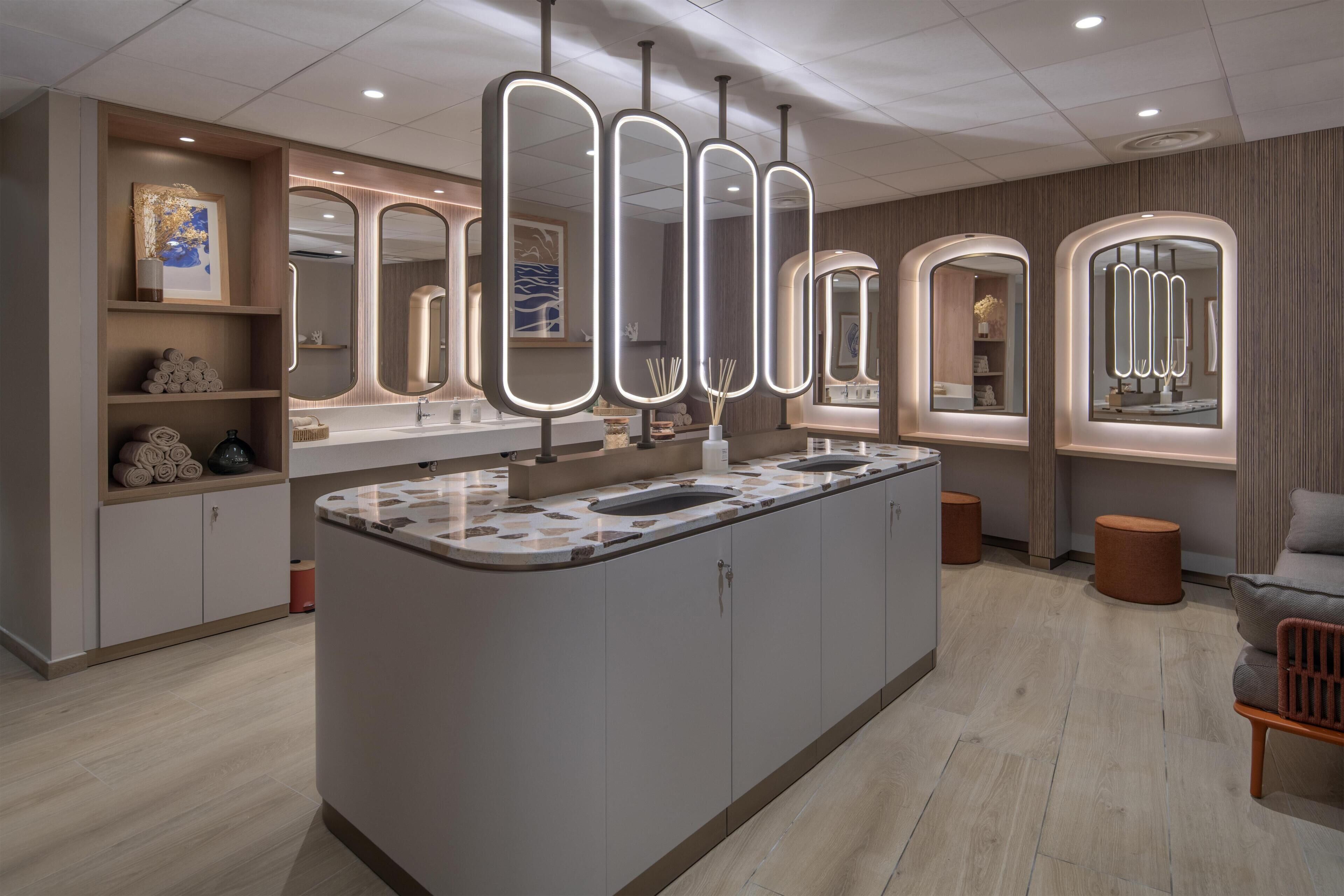 A modern bathroom with a central island, multiple mirrors, and a wooden vanity.