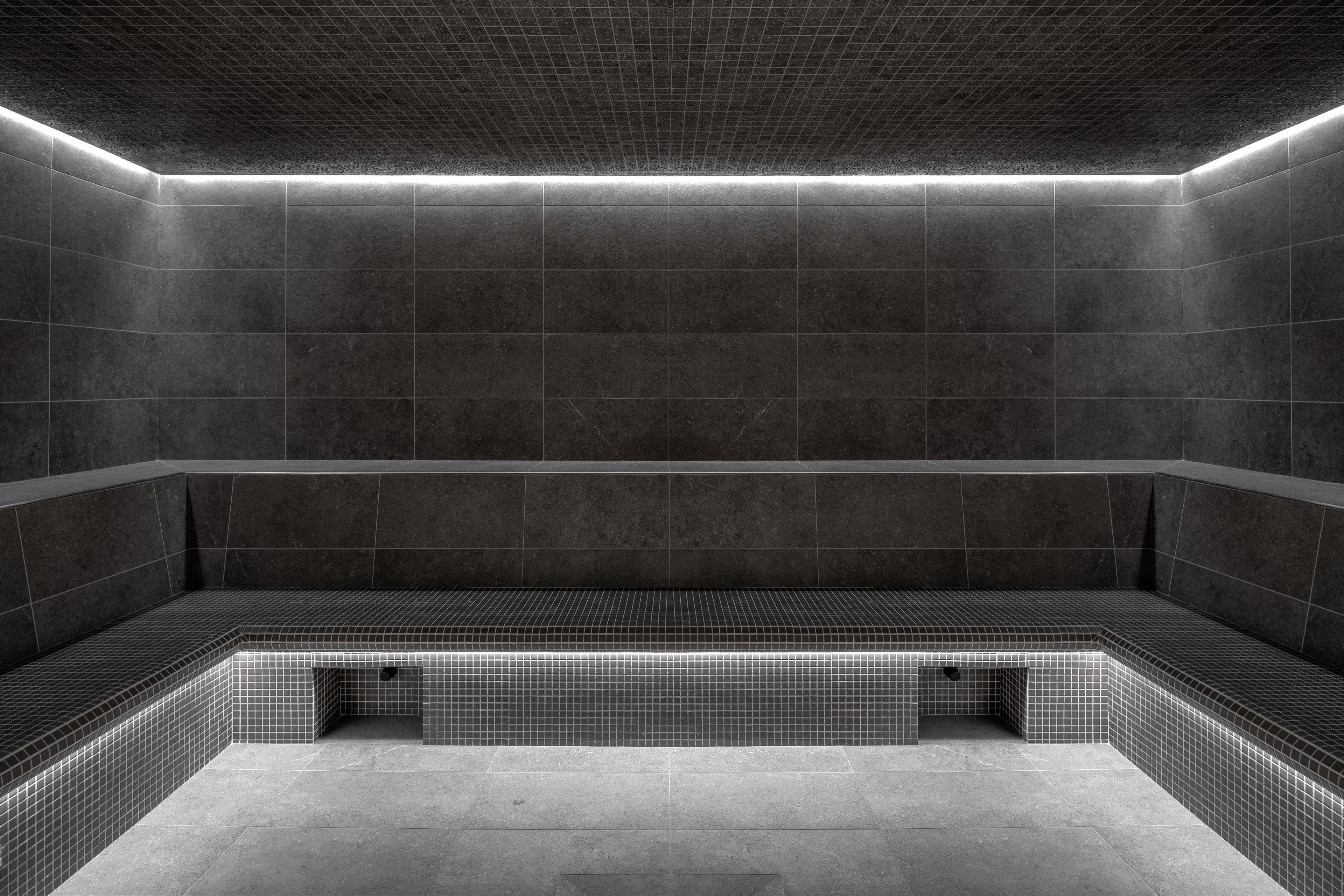 Zona benessere moderna, con scarsa illuminazione, che include una piscina rettangolare e pareti piastrellate.